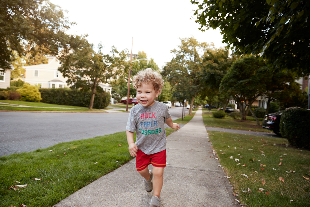 Toddler boy running in a quiet residential street.