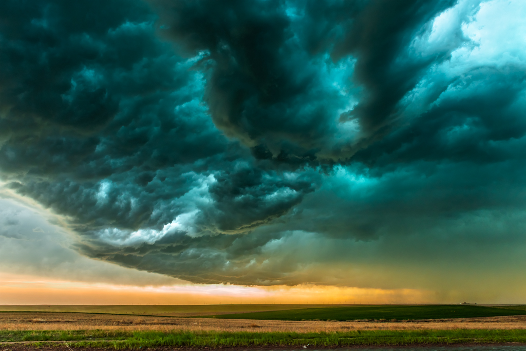 Storm over field in Oklahoma. A mezocyclone storm with dark, gray clouds forming over the plains in Tornado Alley, Oklahoma at sunset.